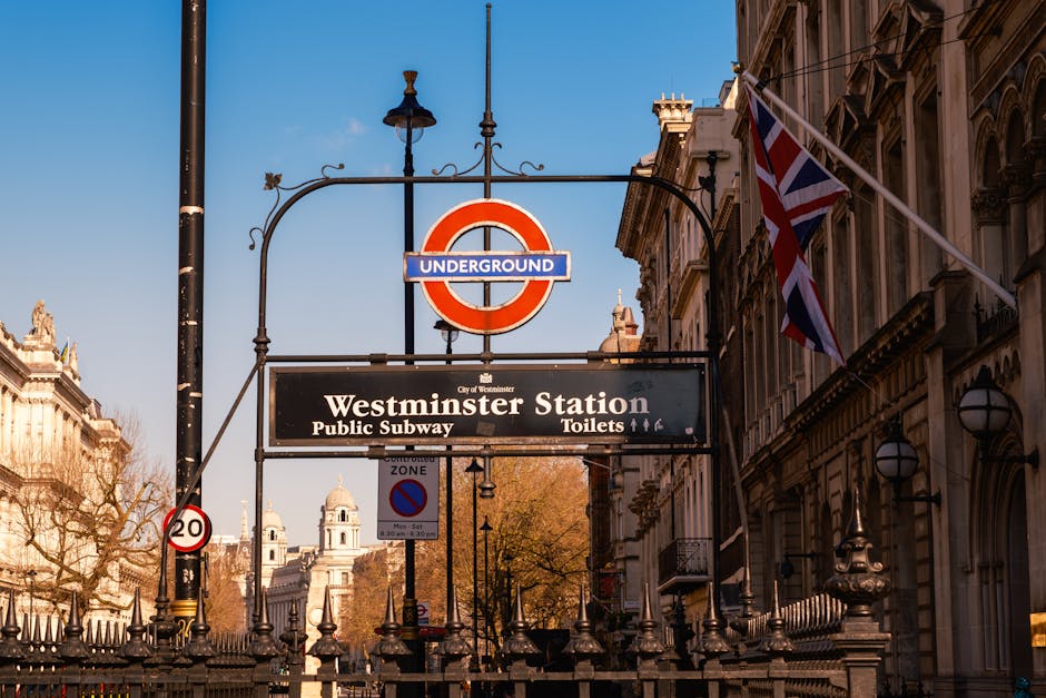 A close-up view of the Westminster Station signage in London, featuring the iconic red and blue London Underground roundel with the text 'Westminster Station' on a black background. The sign is mounte