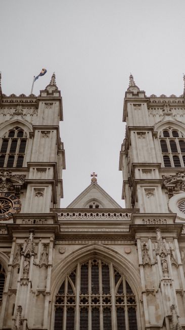 This image features a close-up view of the ornate facade of Westminster Abbey, showcasing its historic Gothic architecture with detailed stone carvings, pointed arches, and tall, narrow windows. The s